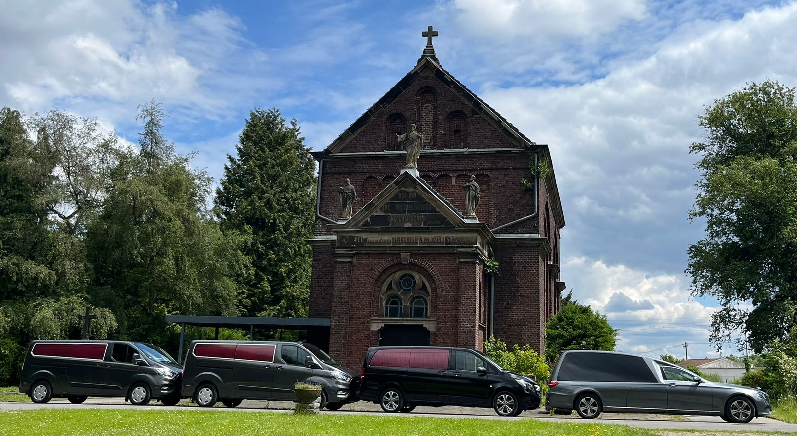 Die Fahrzeugflotter vor der Kirche auf dem Friedhof in Aachen